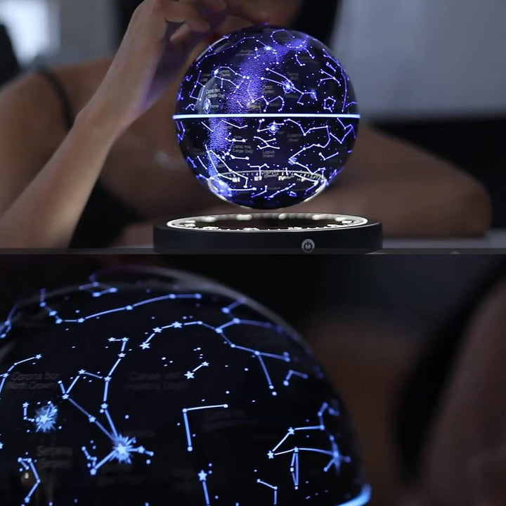 A hand gently touching the glowing blue floating globe above its base with a close-up of the constellation details below.