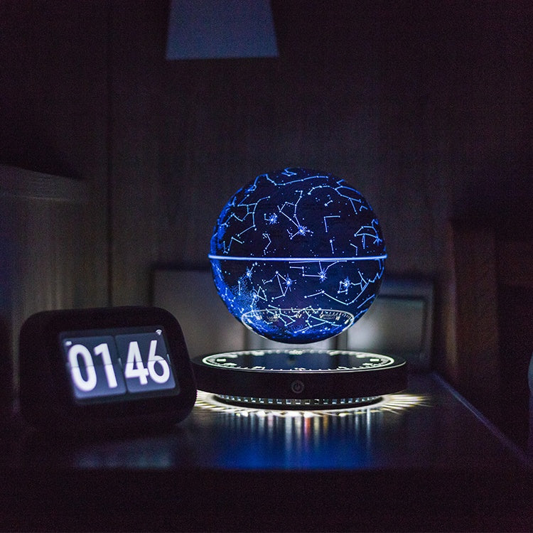 Blue glowing globe floating above its base on a nightstand beside a digital clock.