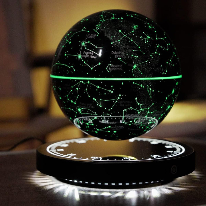 Black star map globe floating above its round base with glowing constellation lines and white light under the base.