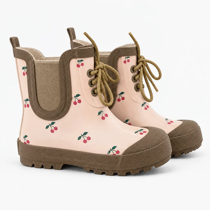 Pair of light pink rain boots with a red cherry print, brown trim, elastic side panels, tan laces and lugged brown soles. 7