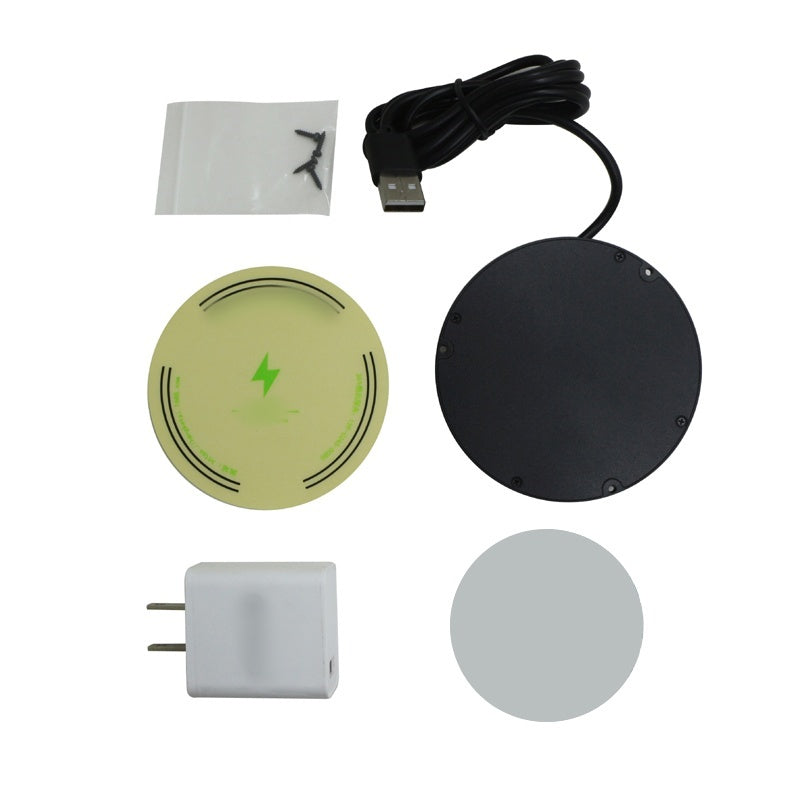 Flat lay of included items: black charger with USB cable, small bag of screws, green alignment sticker, gray adhesive disc and white wall plug.
