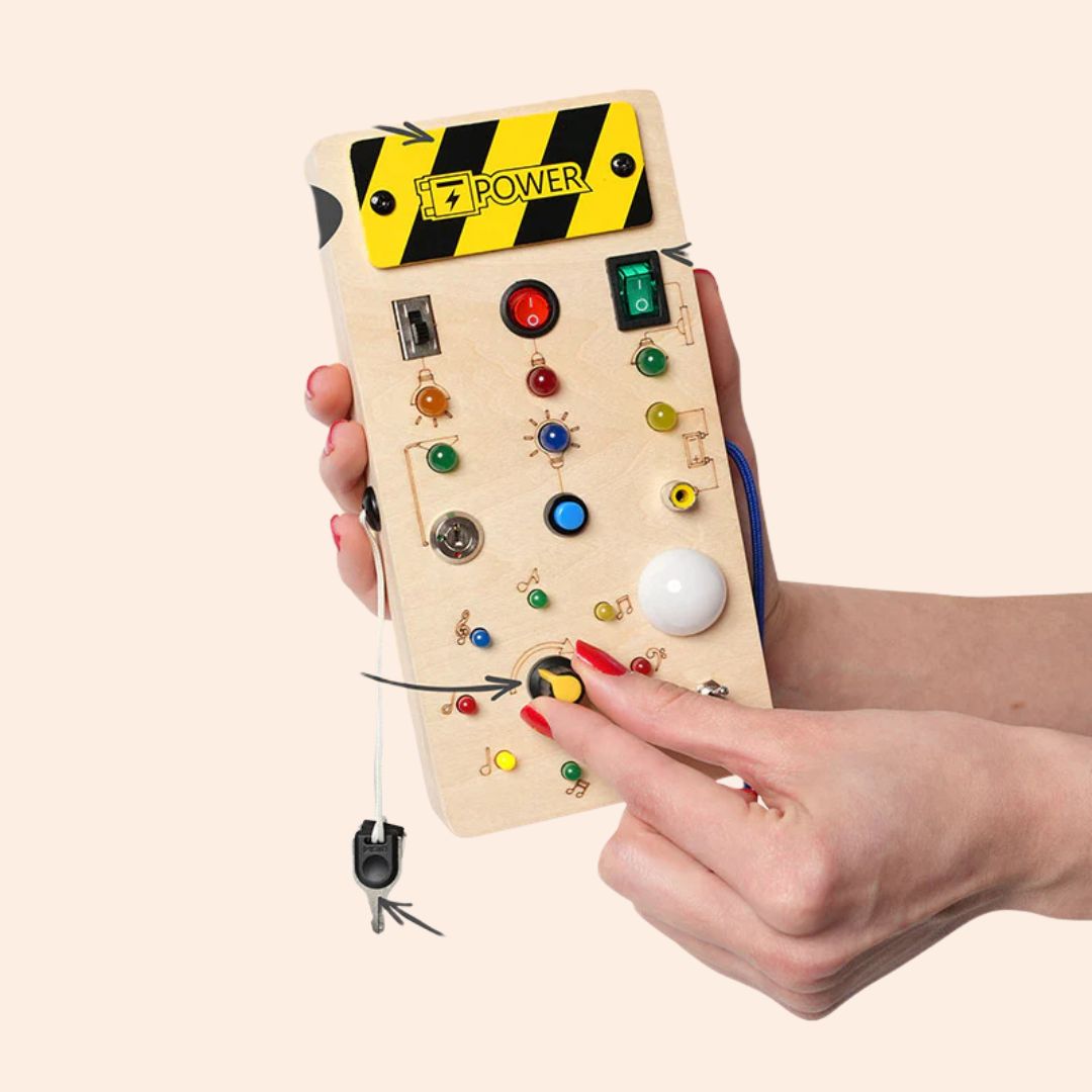 Montessori LED busy board another view with adult hands holding it upright while a finger turns the yellow knob.