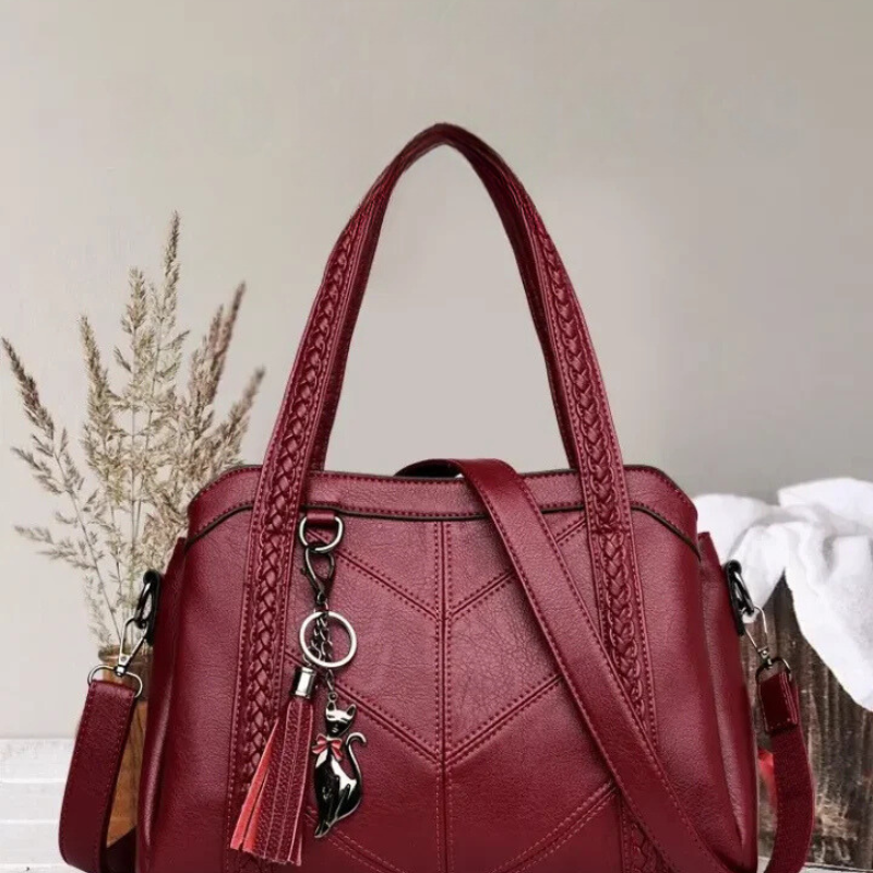 Red leather handbag with braided top handles and a detachable shoulder strap, another view.