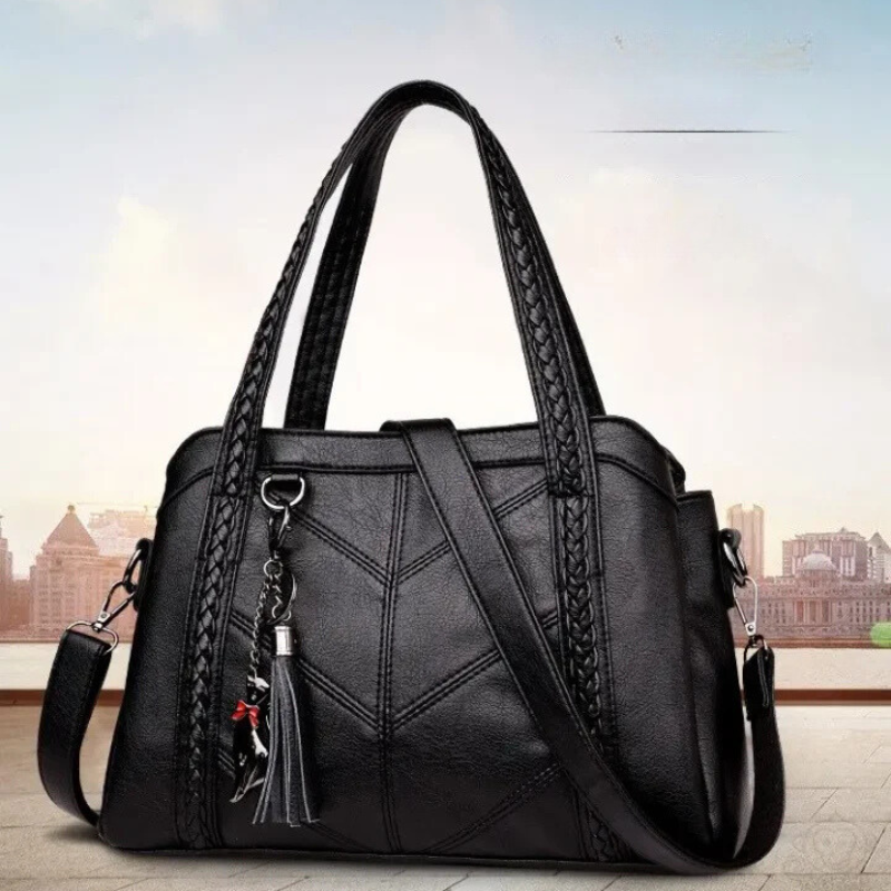 Black leather handbag with braided handles and a cat charm, another view.