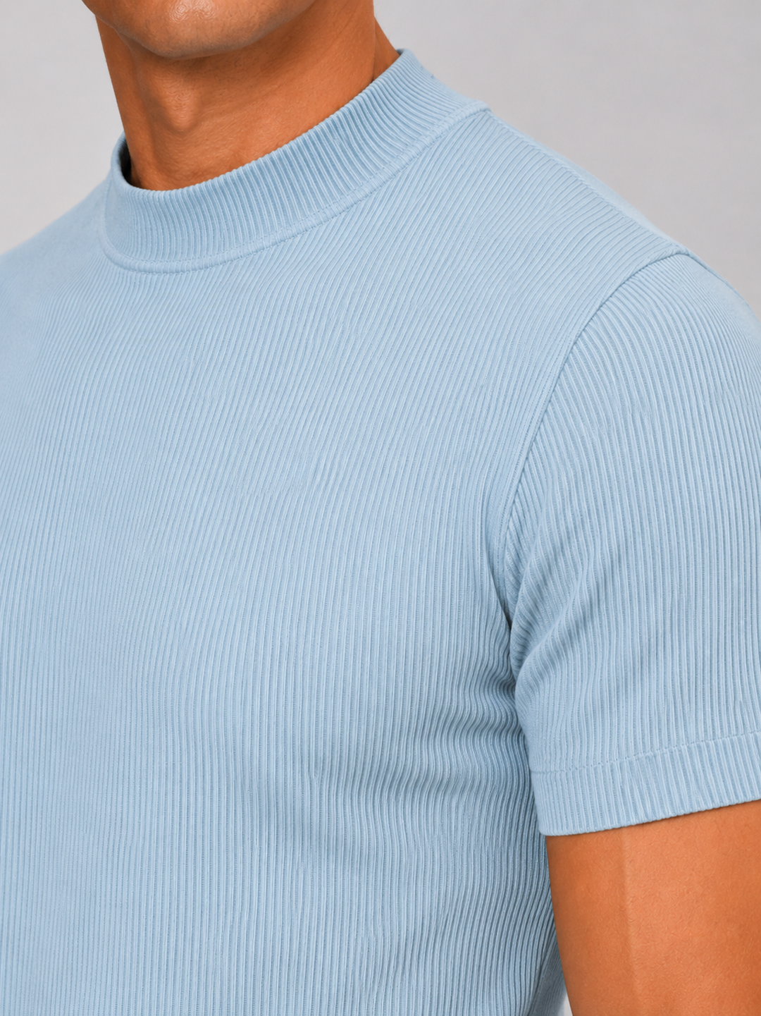 Close-up of the light blue ribbed fabric, mock neck collar and short sleeve hem on a men's tee.