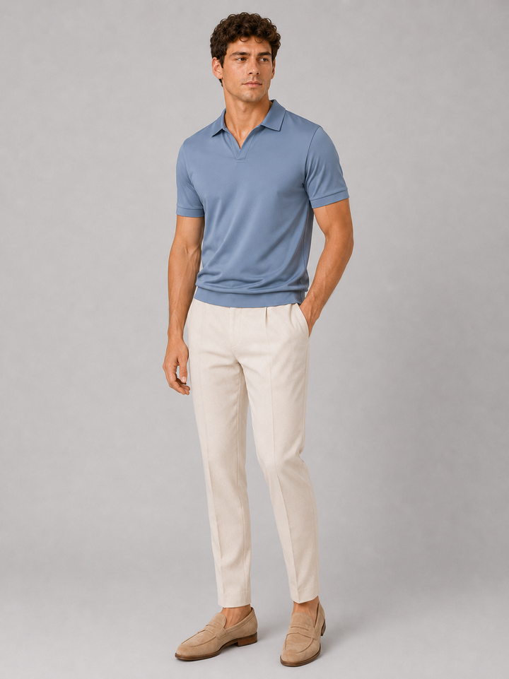 Dusty blue silky touch polo shirt front view styled with cream trousers and tan loafers.