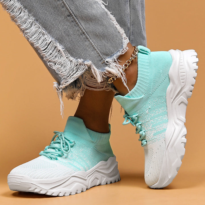 Mint green and white gradient knit sneakers with chunky white soles, worn with ripped gray jeans.