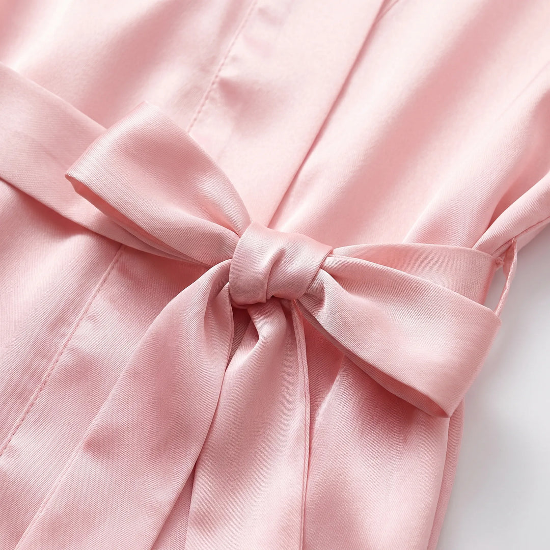 Close-up of the pink satin belt tied in a bow at the waist, showing the sheen of the fabric and seam lines. 5