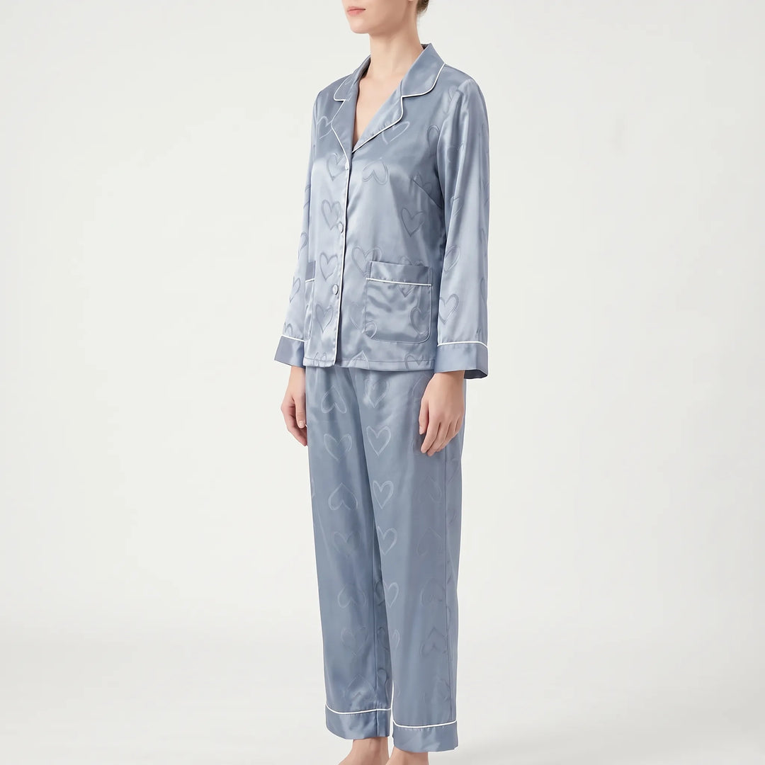 Three-quarter side view of the blue pajama set worn by a model, showing a patch pocket and piped cuffs. 4