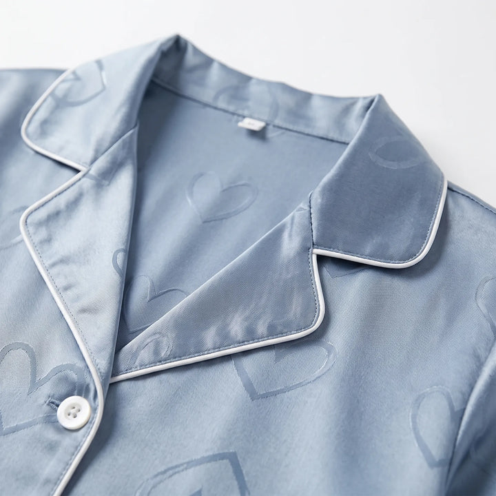 Close-up of the blue satin collar with white piping, a pearly button and the tonal heart jacquard weave. 5