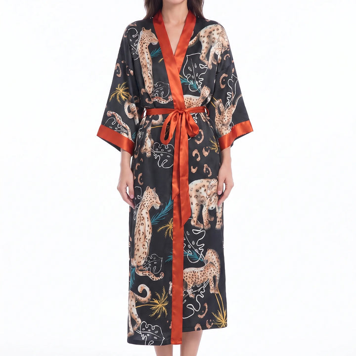Model in a black satin kimono robe with rust orange trim and belt, printed with leopards, palm fronds and monstera leaves. 8