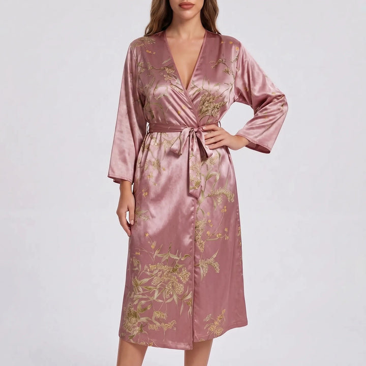 Model wearing the robe in dusty rose pink satin with a gold and olive floral print, deep V-neck and tied belt. 10