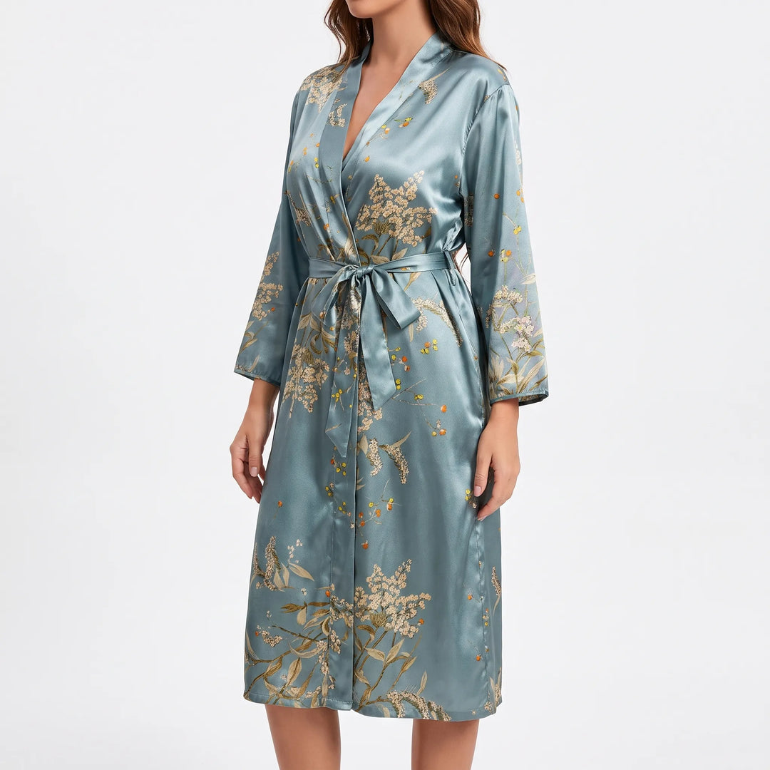 Side three-quarter view of the blue-green satin robe belted at the waist, showing the sleeve print and knee-length hem. 7