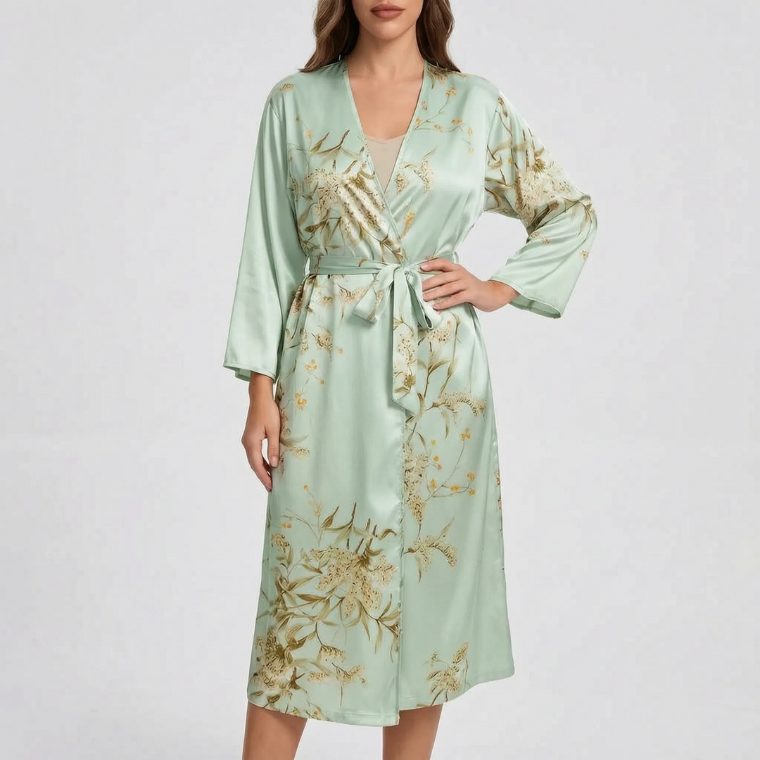 Model wearing the robe in pale mint green satin with a gold and olive floral print, belt tied, hand on hip. 8