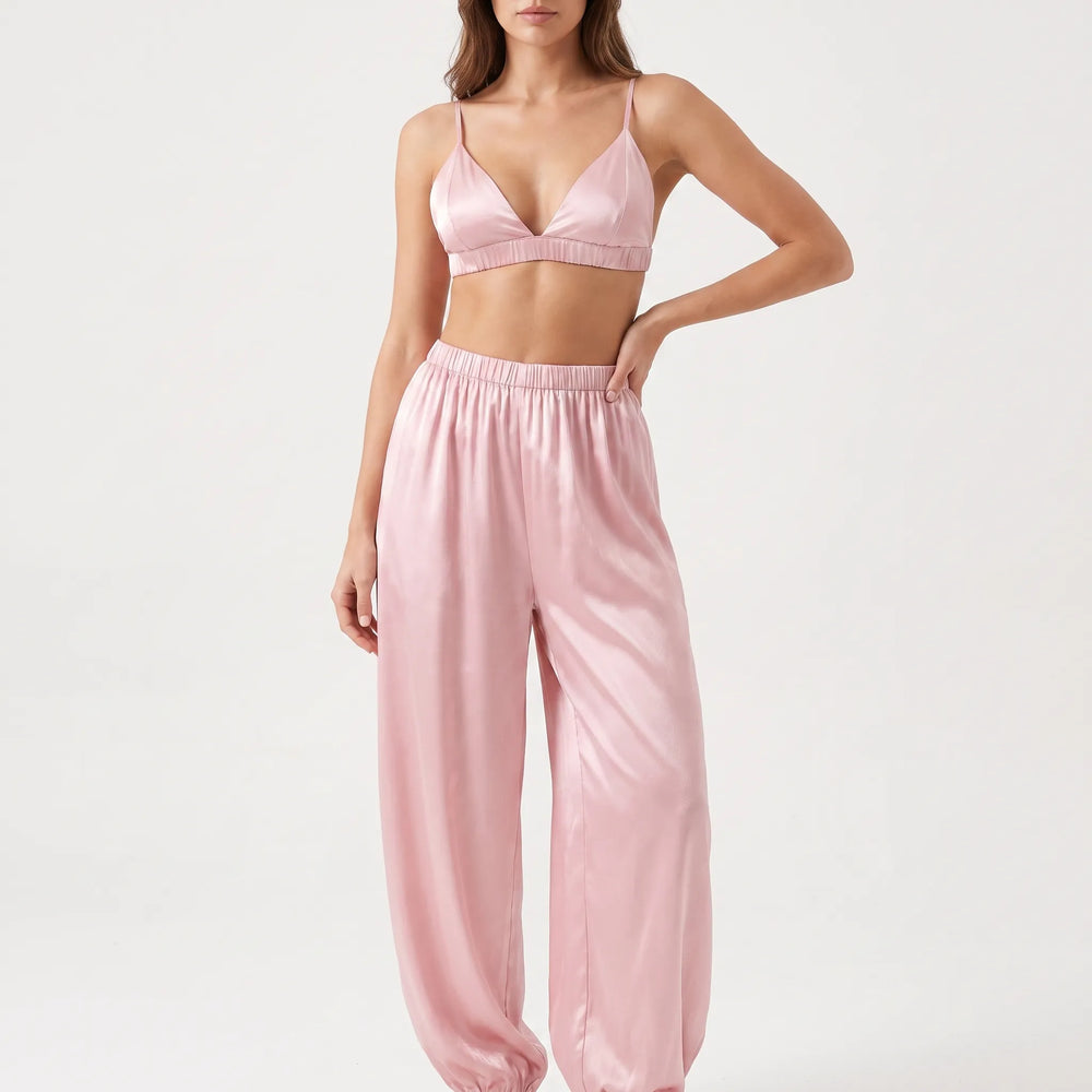 Model in studio with one hand on hip, wearing the pink satin triangle bralette and wide-leg pants with elastic cuffs. 2