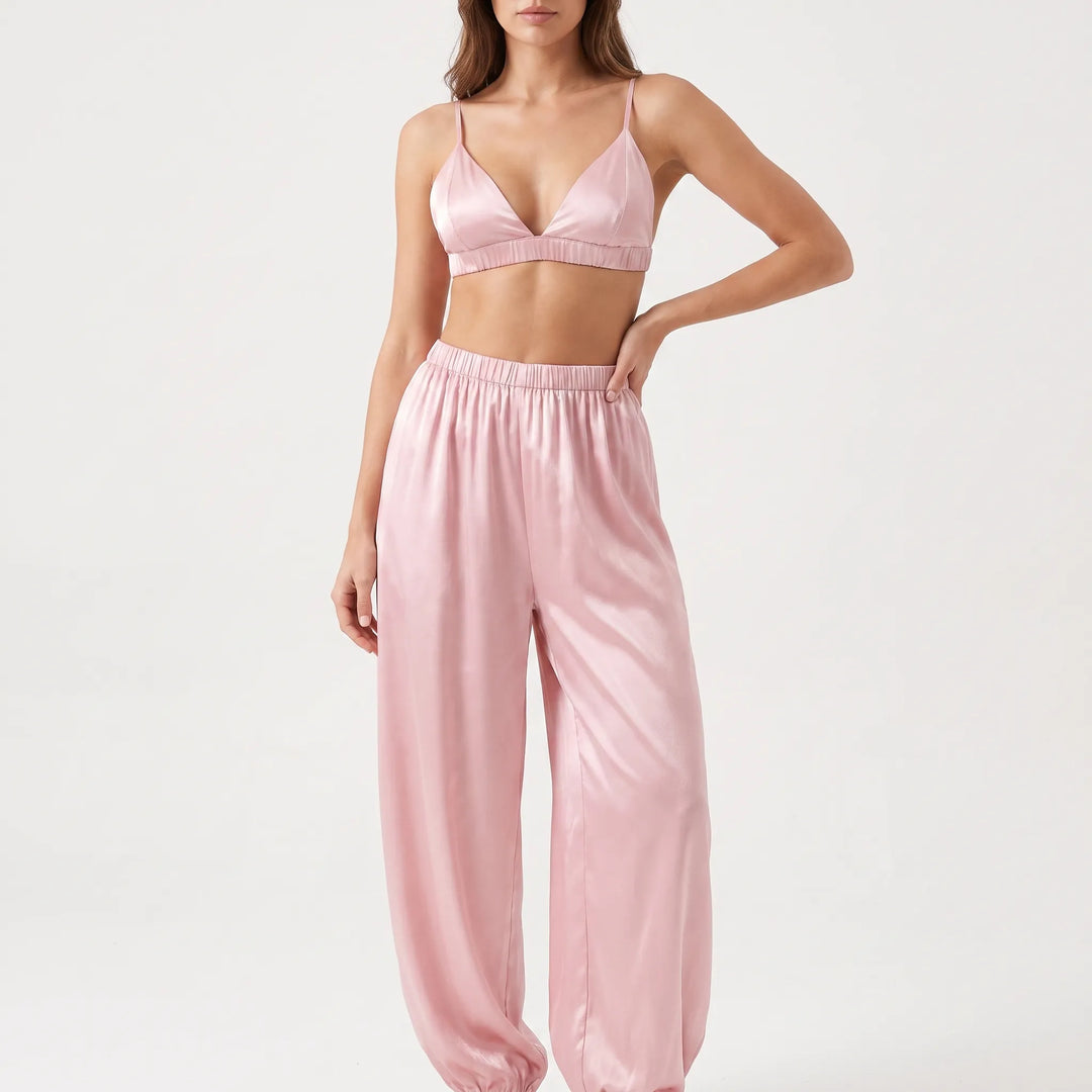 Model in studio with one hand on hip, wearing the pink satin triangle bralette and wide-leg pants with elastic cuffs. 2