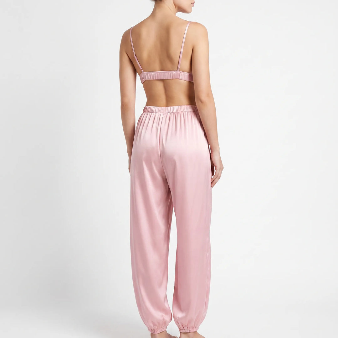 Back view of model in the pink satin set, showing thin adjustable bralette straps and the elastic waistband of the pants. 3