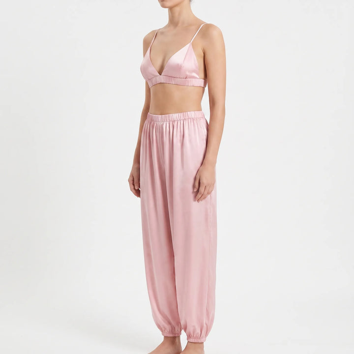 Three-quarter side view of model in the pink satin bralette and relaxed pants with gathered ankle cuffs. 4