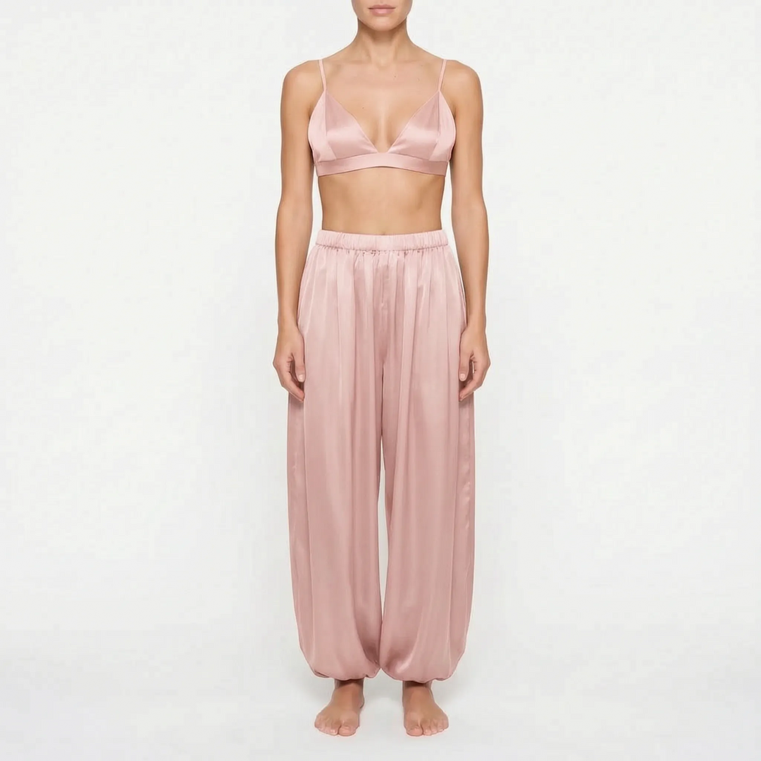Front view of model in the dusty rose satin version of the triangle bralette and gathered-ankle pants. 7