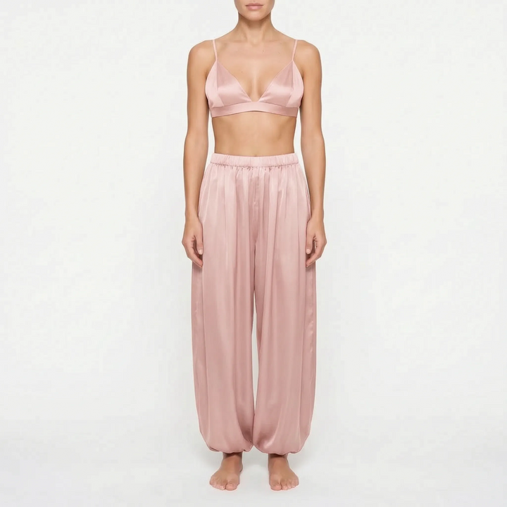 Front view of model in the dusty rose satin version of the triangle bralette and gathered-ankle pants. 7