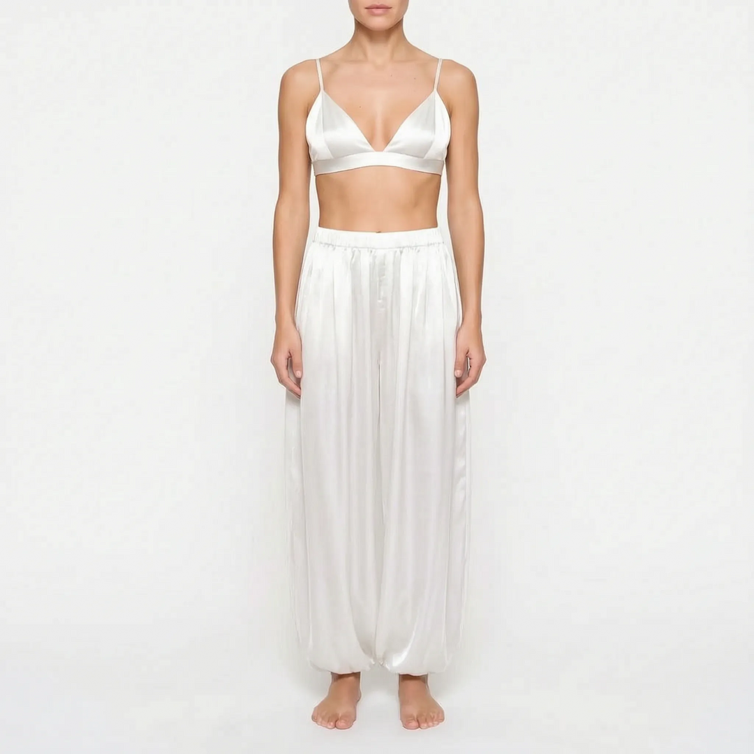 Front view of model in the ivory white satin version of the triangle bralette and full pants with gathered ankles. 8