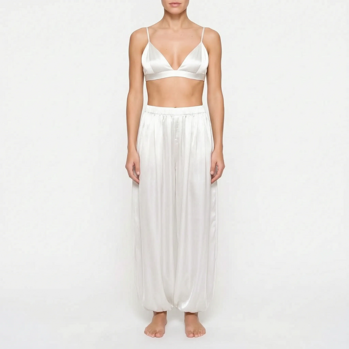 Front view of model in the ivory white satin version of the triangle bralette and full pants with gathered ankles. 8