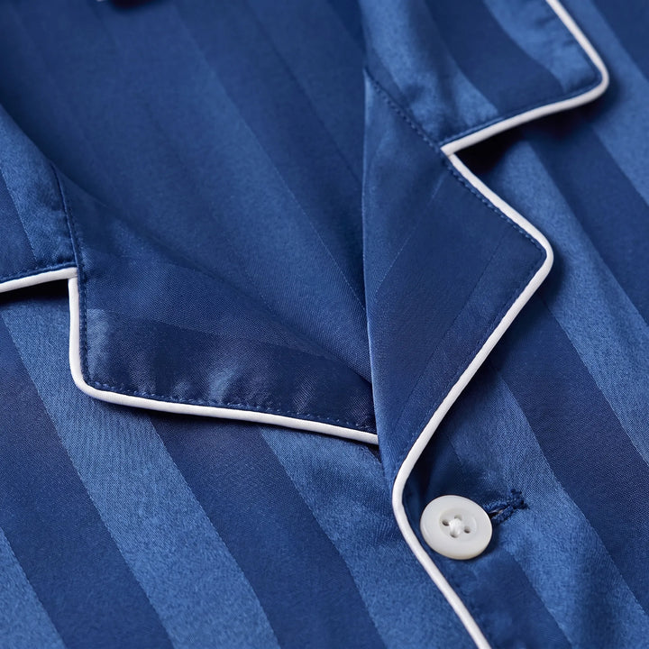 Close-up of the notched collar with white piping, a white button and the tonal stripe weave of the navy satin fabric. 5