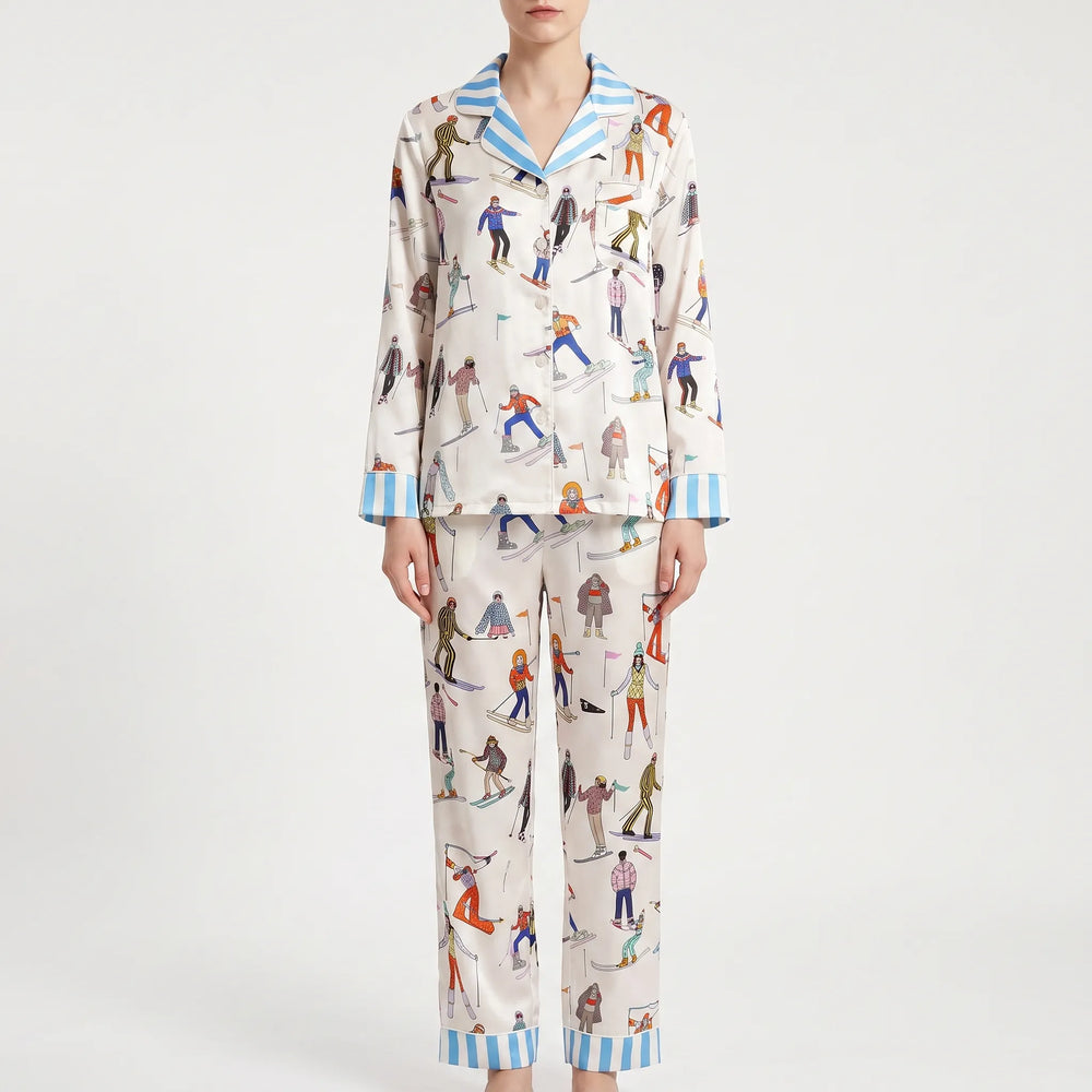 Front view of the long sleeve pajama set on a model, showing cream skier print, button front, chest pocket and blue striped trim. 2