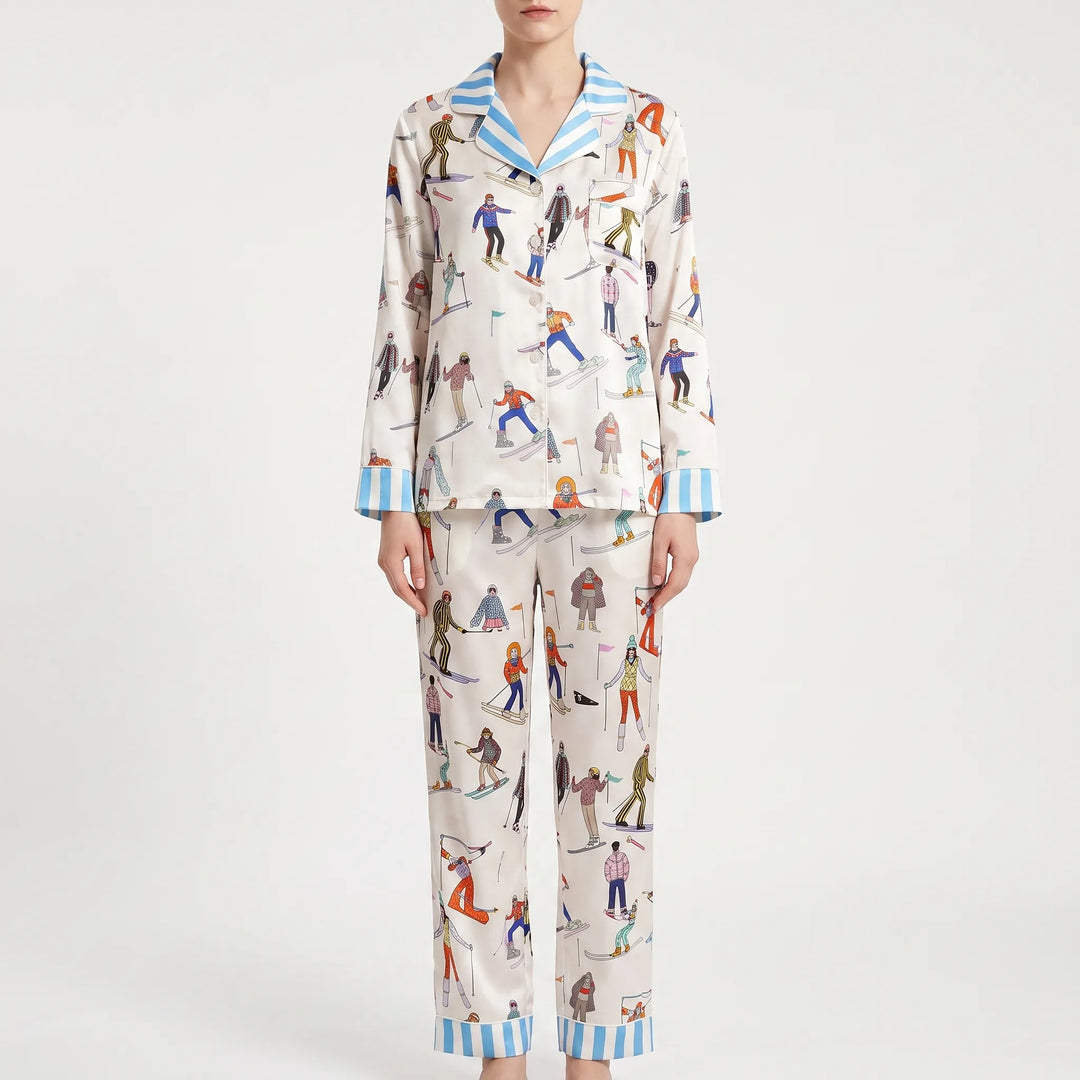 Front view of the long sleeve pajama set on a model, showing cream skier print, button front, chest pocket and blue striped trim. 2