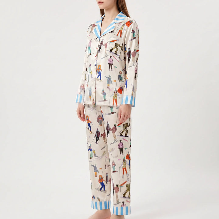 Three-quarter side view of the model wearing the skier print pajama set with striped collar, chest pocket and cuffed pant hems. 4