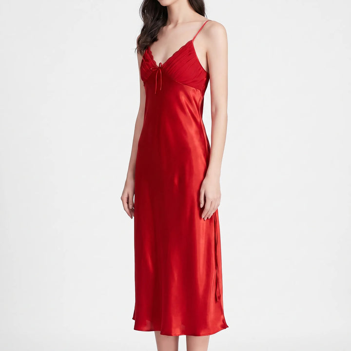 Front three-quarter view of the red satin nightdress on a model against white, with pleated V-neck bodice and bow. 2