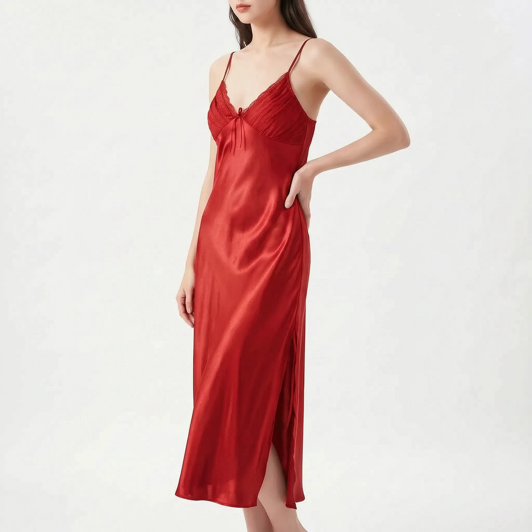 Model with hand on hip wears the long satin nightdress in deep red, with lace-edged pleated bodice and side slit. 8