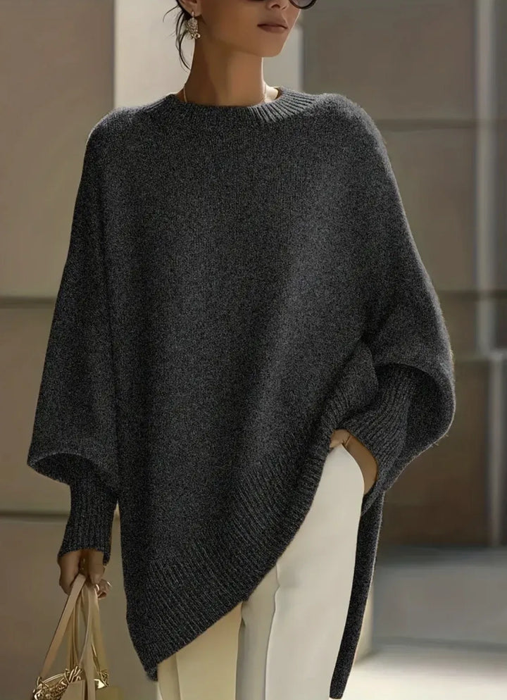 Charcoal heathered knit sweater with ribbed cuffs and asymmetric hem, worn with white trousers and a handbag 12