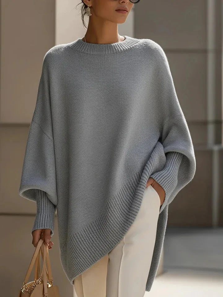 Gray oversized sweater with drop shoulders and ribbed cuffs, styled with white trousers and a tan bag 17