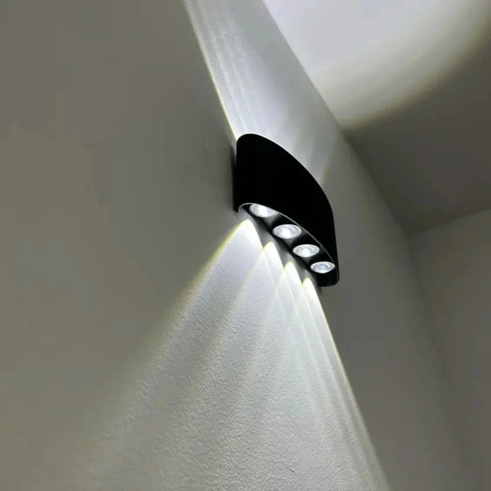 Black wall light detail with four LEDs on its underside, throwing bright white beams across a wall corner.