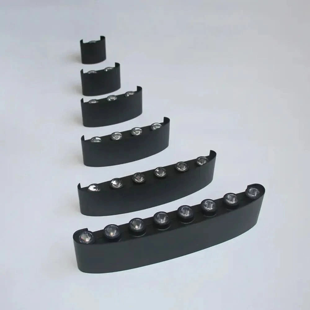 Another view of six black wall light bodies lined up, showing models with from one to eight LEDs on each.