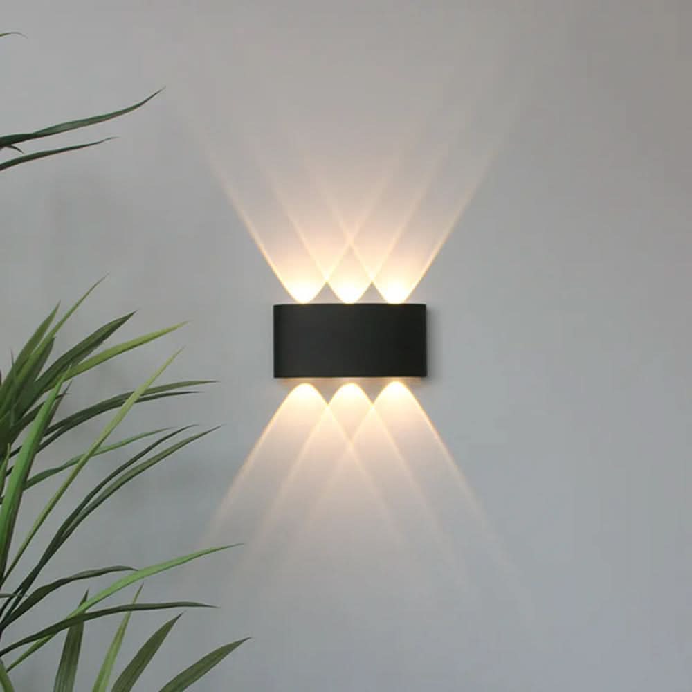 Black oval wall light detail with three beams up and three down, overlapping into diamond patterns on a gray wall.