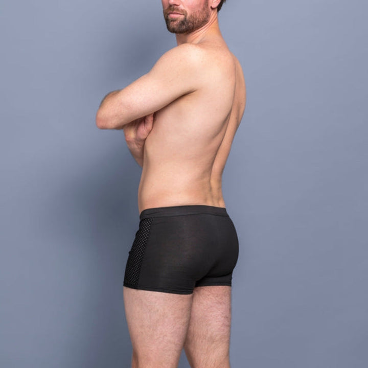Side and rear view of a bearded man with crossed arms wearing black boxer briefs with a perforated mesh side panel. 7