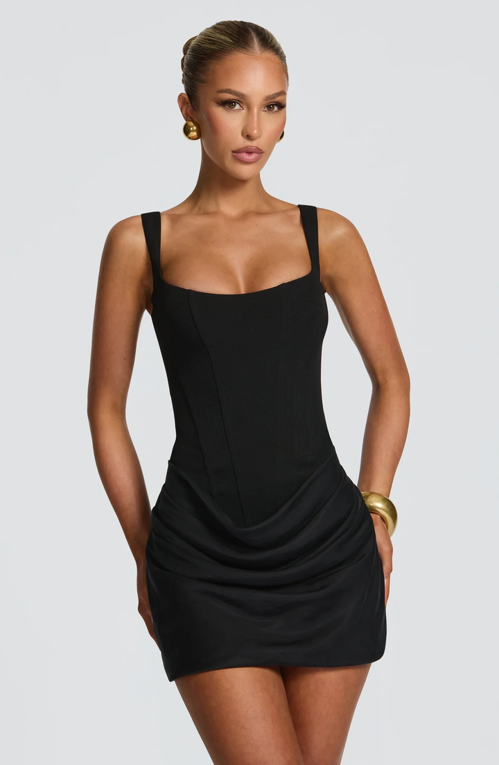 Black mini dress with a structured bodice and draped skirt, front view.