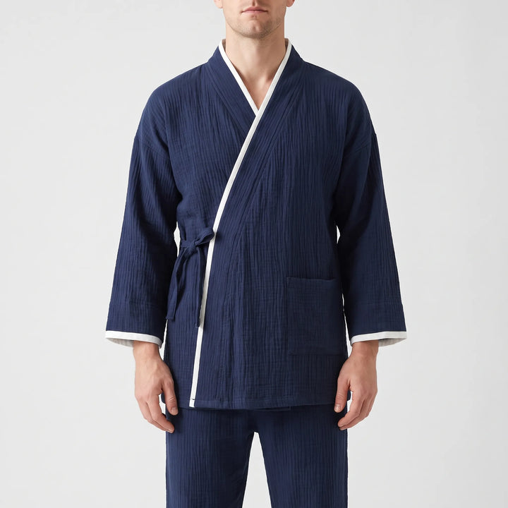 Close front view of a navy wrap-style pajama top with white piping, side tie, patch pocket, and wide sleeves. 2