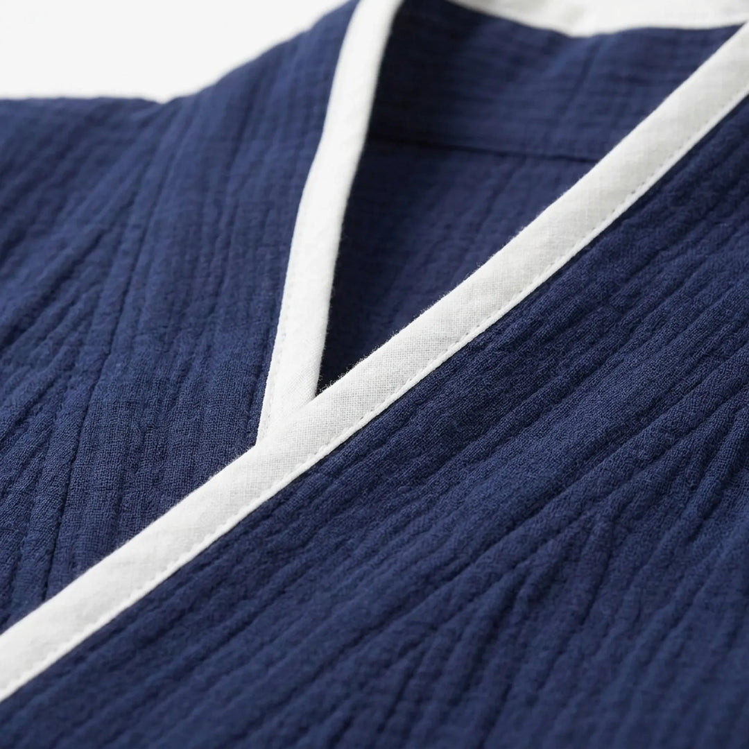 Close-up detail of the navy crinkled cotton fabric and white piped V-neck edge of the wrap top. 5