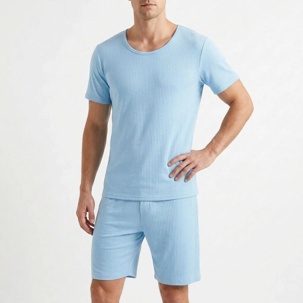 Man in the light blue ribbed pajama tee and shorts posing against a plain white background with one hand on his hip. 2