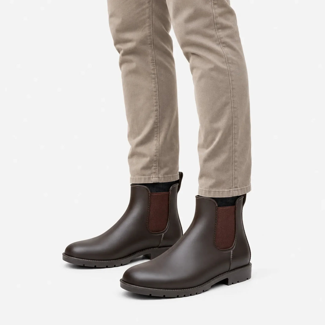 Brown matte rain boots with elastic side panels worn with khaki pants, shown from a three-quarter angle on white. 5
