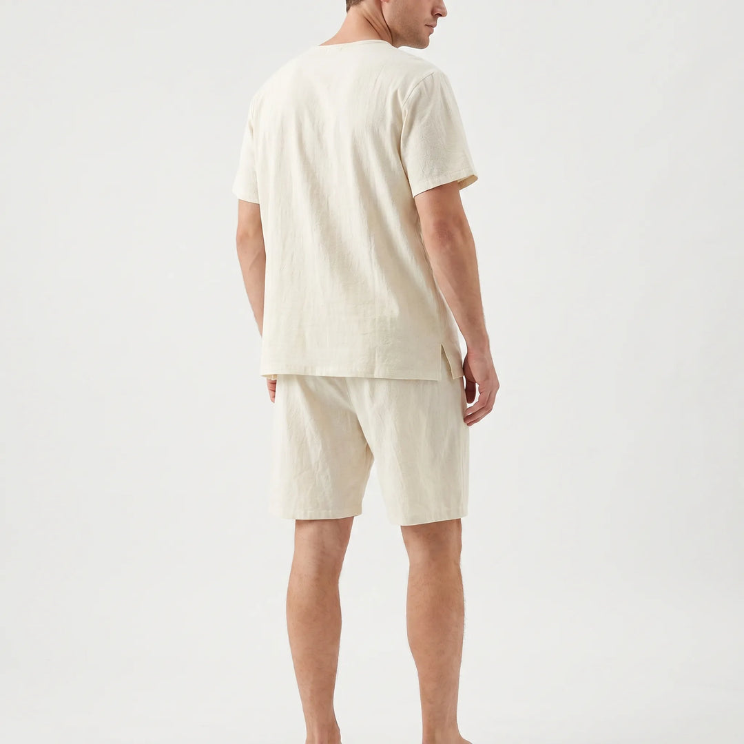 Back view of the cream pajama set on a model, showing the small side slit at the tee's hem and the shorts. 3