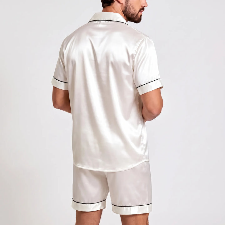 Back view of the white satin pajama set on a model, showing the smooth shirt back, curved hem, and piped short cuffs. 3