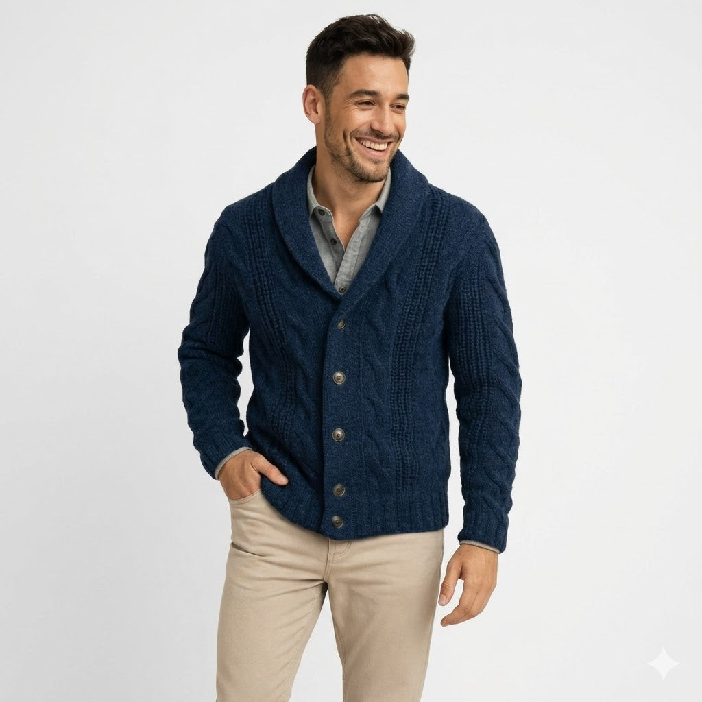 Smiling man in navy cardigan over a gray shirt and khakis, hand in pocket, waist-up view 1