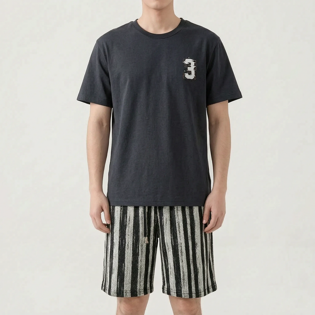 Model wearing a dark charcoal tee with a small graphic on the chest, paired with black and white vertically striped drawstring shorts. 14