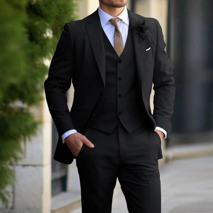 Same three-piece suit in black, worn with a white shirt, brown tie and dark boutonniere 4