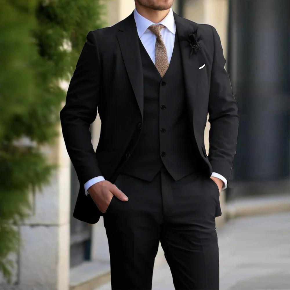 Model in a black three-piece suit with white shirt and brown tie, standing outdoors with hands in pockets 3