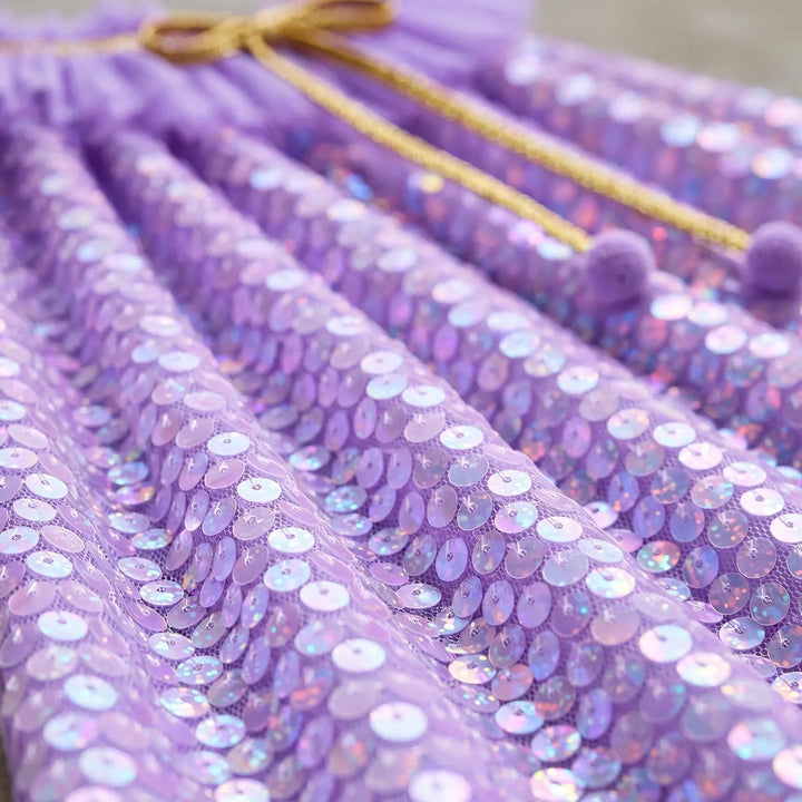 Close-up of the iridescent lavender sequins on the cape, with gold cord and purple pom-poms 3